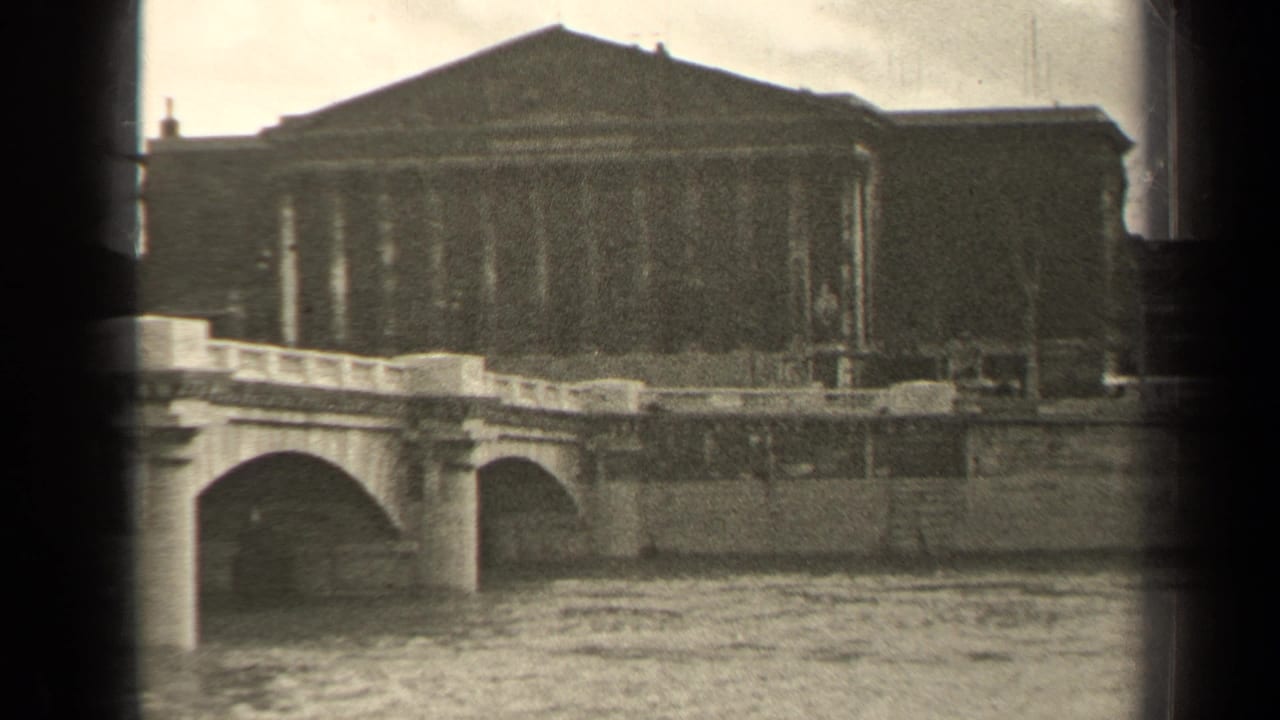 1947 Paris frame with a stone arch bridge crossing the river below a large classical facade.