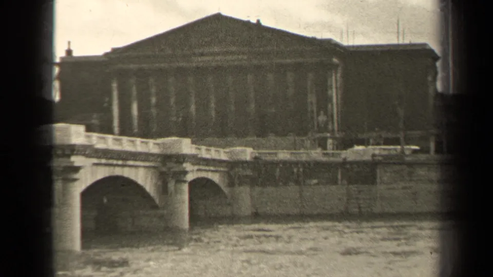 1947 Paris home-movie frame emphasizing the bridge arch, river movement and classical building in the background.