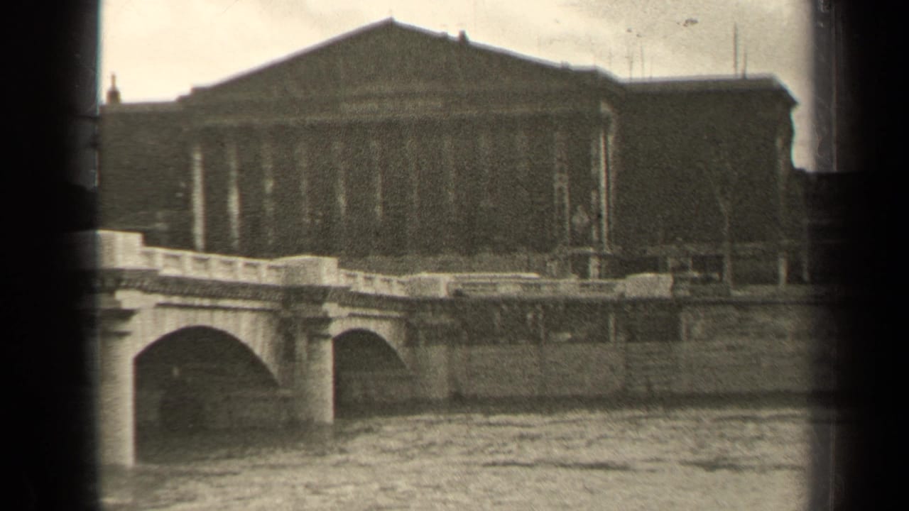 Stone bridge over a river with a large classical building beyond it.