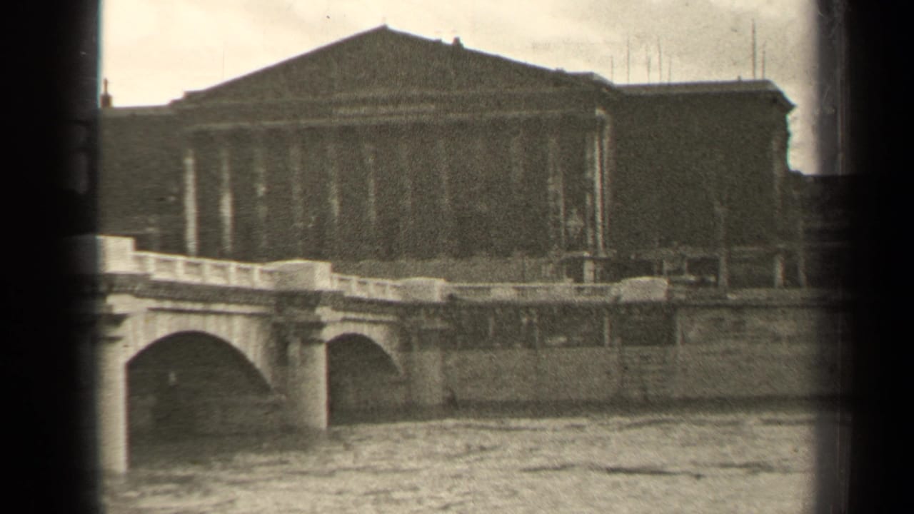 Bridge arches and a large building seen across a river.
