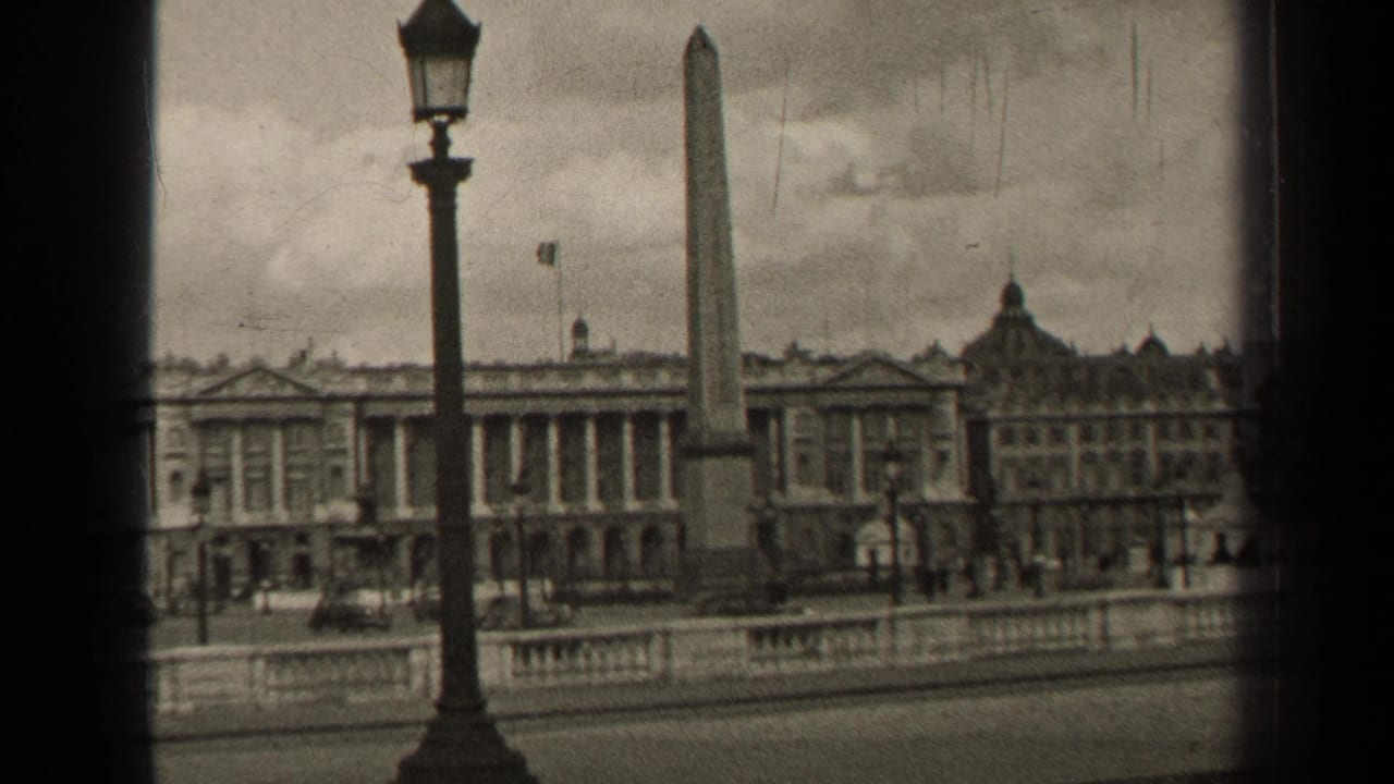 Luxor Obelisk and Paris buildings seen past a lamppost and stone balustrade.