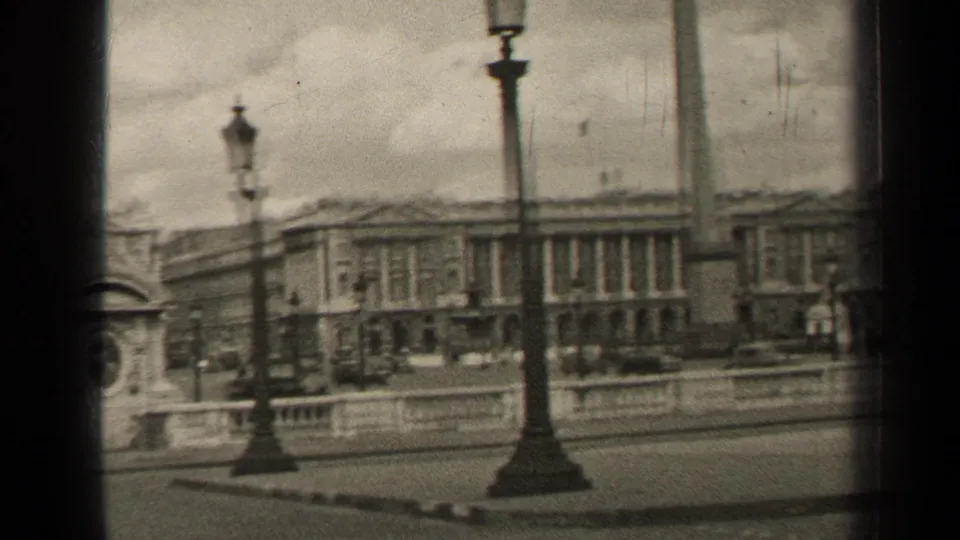 1947 Paris street view with classical facades, tall lampposts, a stone balustrade, and small distant pedestrians.
