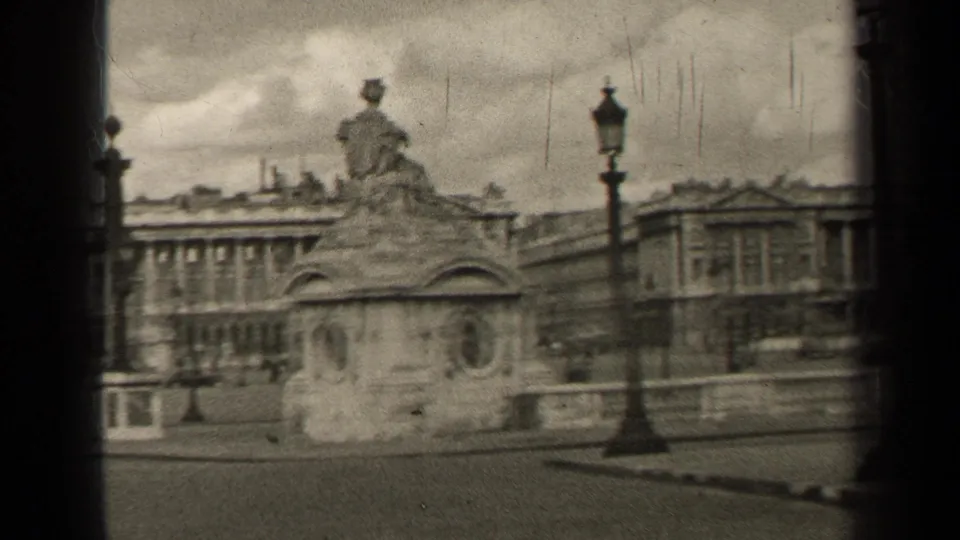 1947 Paris view with a statue on a stone pedestal, an ornate lamppost, large civic buildings, and distant street activity.