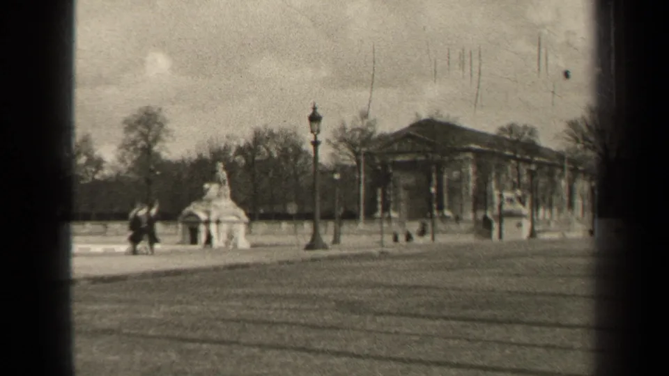 1947 Paris park scene showing distant pedestrians near a small monument, with lampposts and a classical building beyond.
