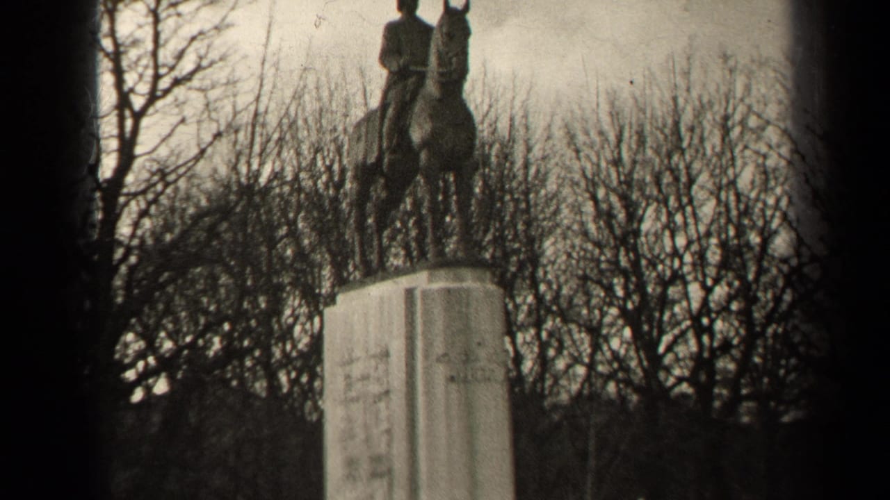Equestrian statue on a tall pedestal with bare trees behind it.
