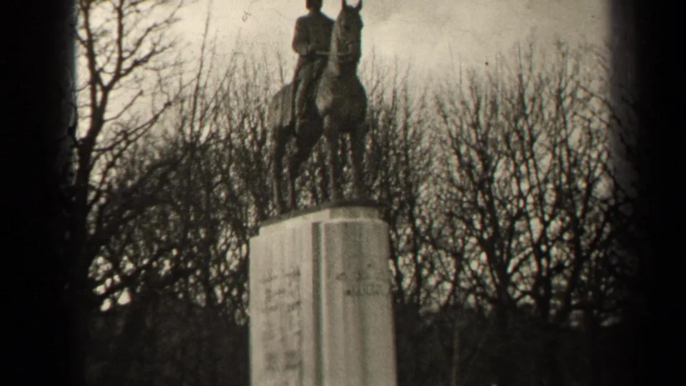 1947 Paris 8mm frame showing a mounted statue above a pale stone pedestal, backed by leafless trees.
