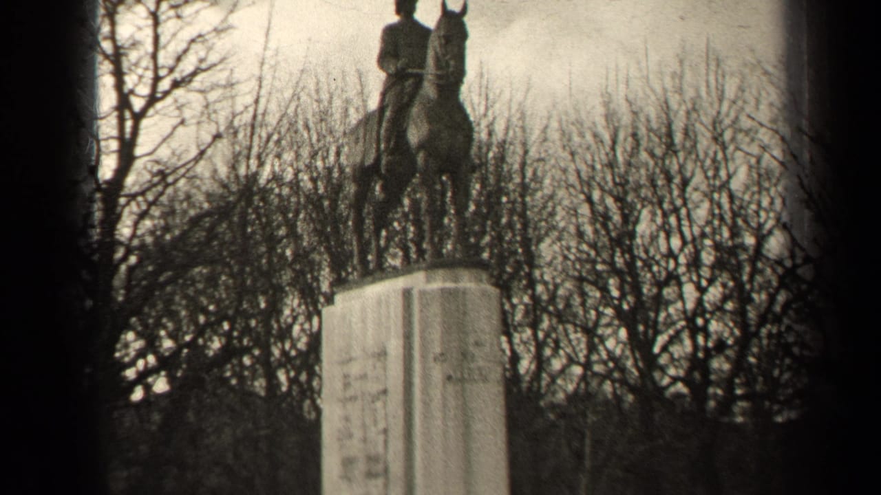 Mounted statue and stone pedestal framed against leafless trees.