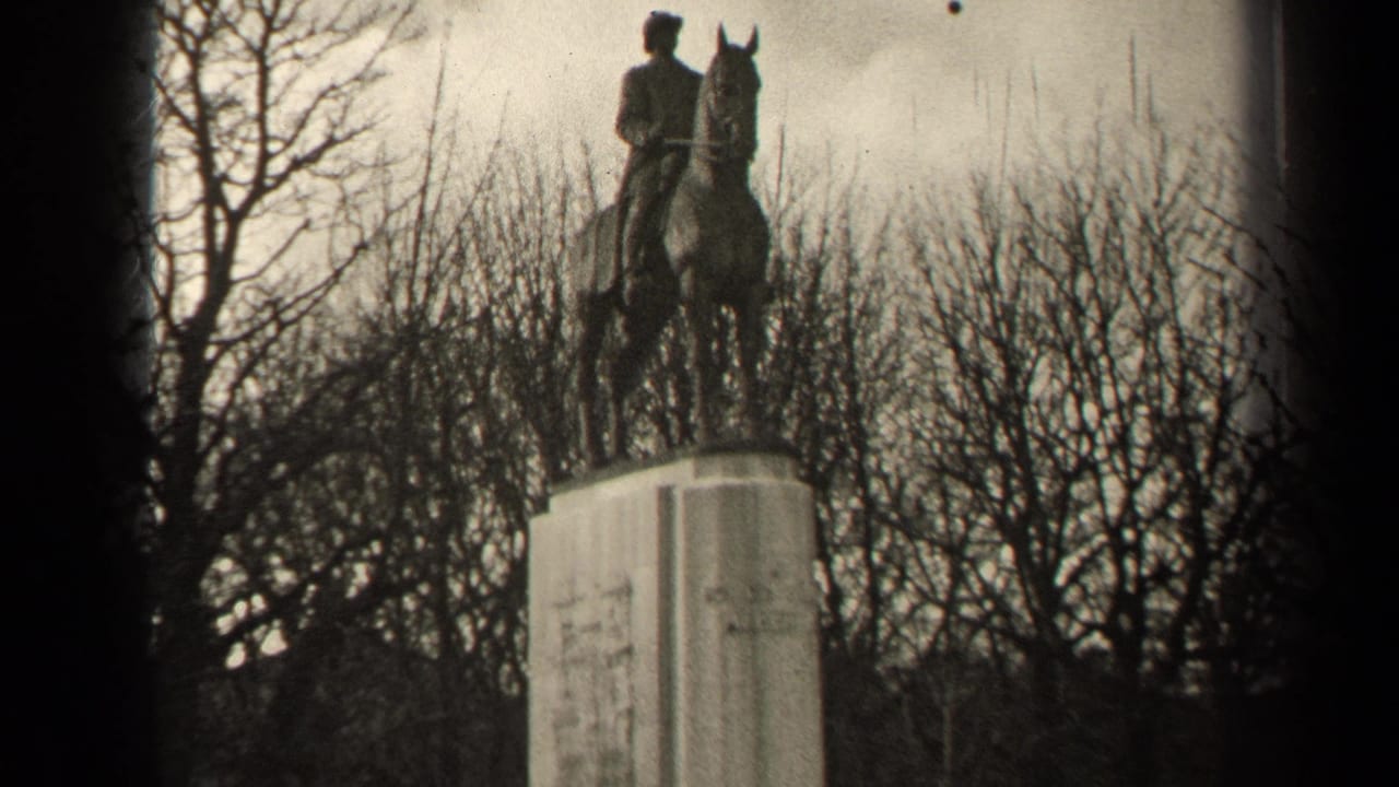 Black-and-white 1947 Paris home-movie frame showing an equestrian monument above a tall pedestal among winter trees.