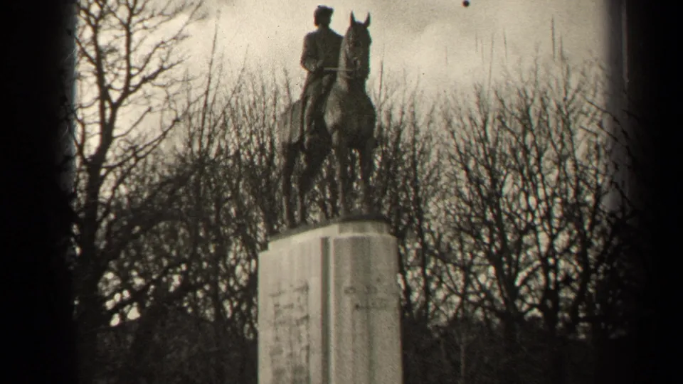 Black-and-white 1947 Paris home-movie frame showing an equestrian monument above a tall pedestal among winter trees.