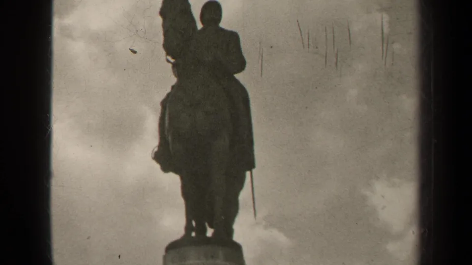 1947 Paris 8mm frame with a silhouetted equestrian statue rising above its pedestal under a cloudy sky.
