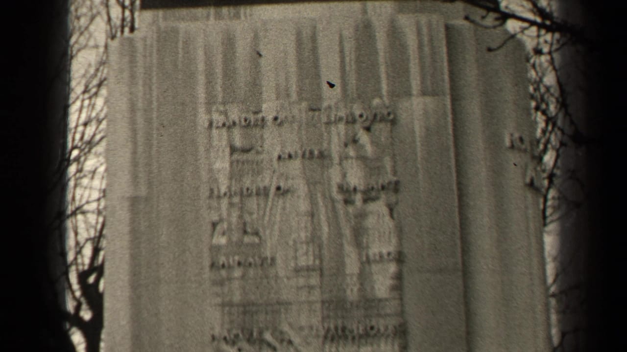 1947 Paris 8mm frame showing a weathered inscribed pedestal of an equestrian monument, with bare branches and soft focus.