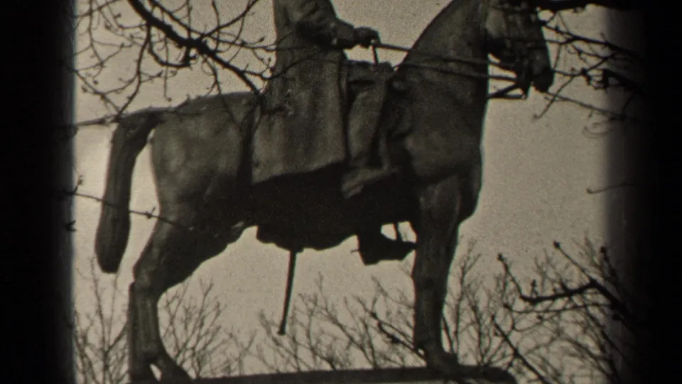 1947 Paris 8mm still of a bronze rider on horseback, photographed from below through leafless branches.