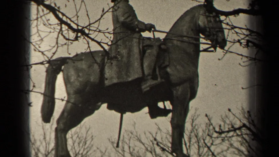 1947 Paris 8mm frame showing a mounted rider statue seen through bare branches against a cloudy sky.