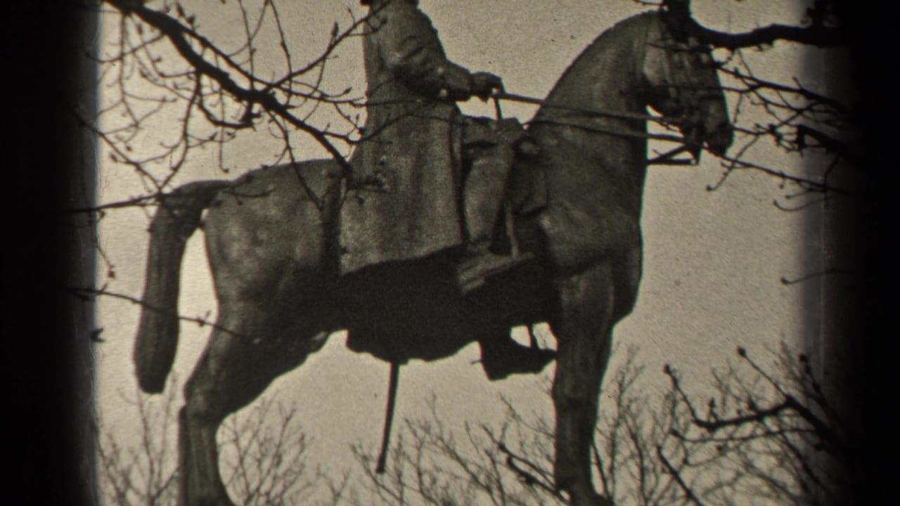 1947 Paris home-movie frame of an equestrian monument, with the horse and rider silhouetted by branches and pale sky.