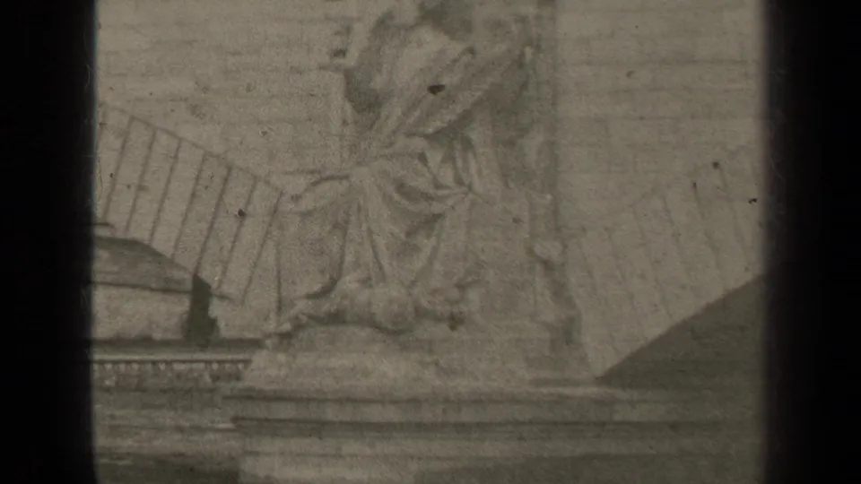 1947 Paris 8mm frame showing a pale, soft-focus draped seated figure sculpture with masonry details and film wear.