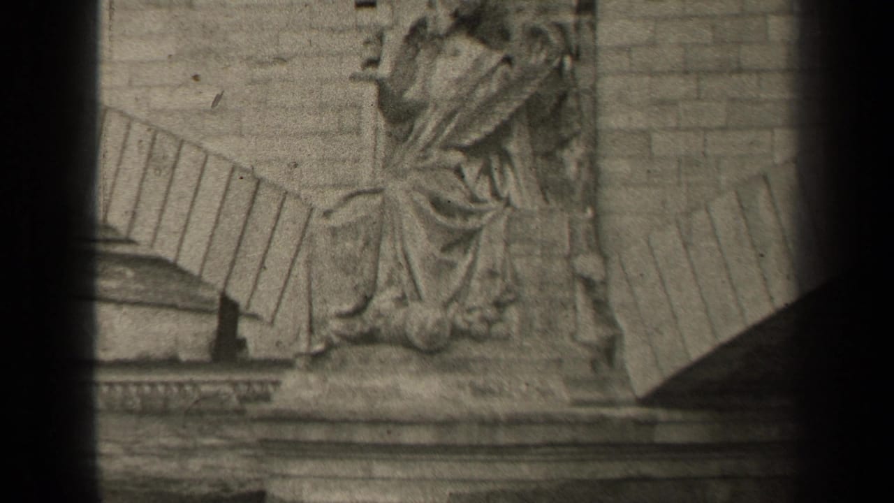 Stone relief sculpture beside river architecture, partly obscured by dark film-frame edges.