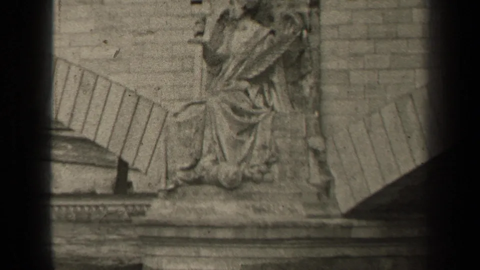 1947 Paris home-movie frame showing a carved stone relief near river architecture, with heavy vignette and soft 8mm grain.
