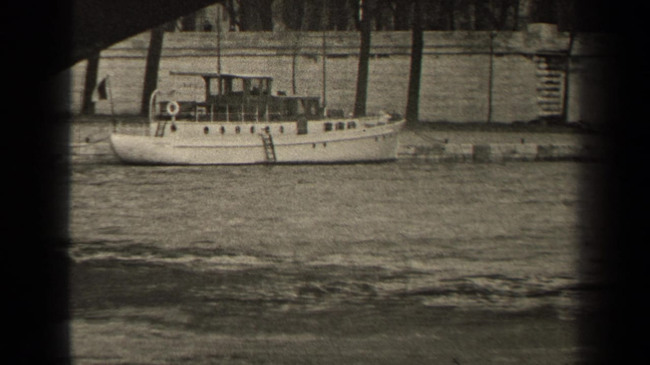 1947 Paris frame showing a small white boat at the river wall under a bridge, with trees and stone embankment behind it.
