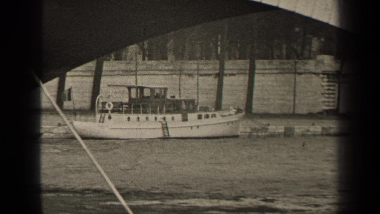 Black-and-white 1947 Paris frame with a stationary motorboat, river wall, bare trees, and the underside of a bridge.