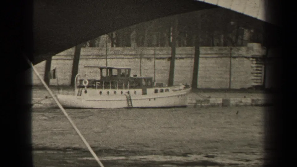 Black-and-white 1947 Paris frame with a stationary motorboat, river wall, bare trees, and the underside of a bridge.
