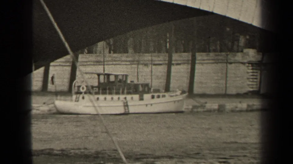 1947 Paris 8mm frame showing a white cabin motorboat at the riverbank, with a diagonal line and bridge shadow in view.