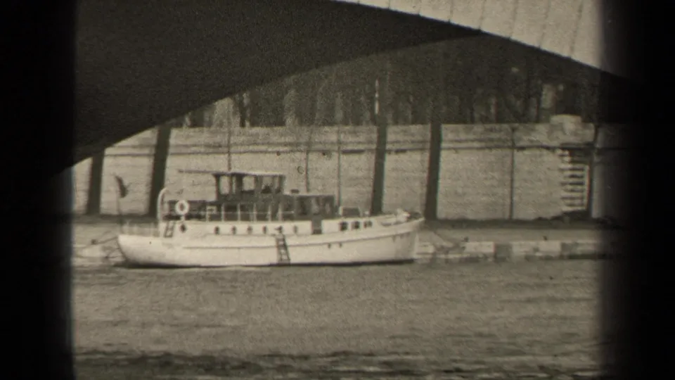 Late-1940s Paris river frame with a small motorboat moored below a bridge and trees visible above the embankment.
