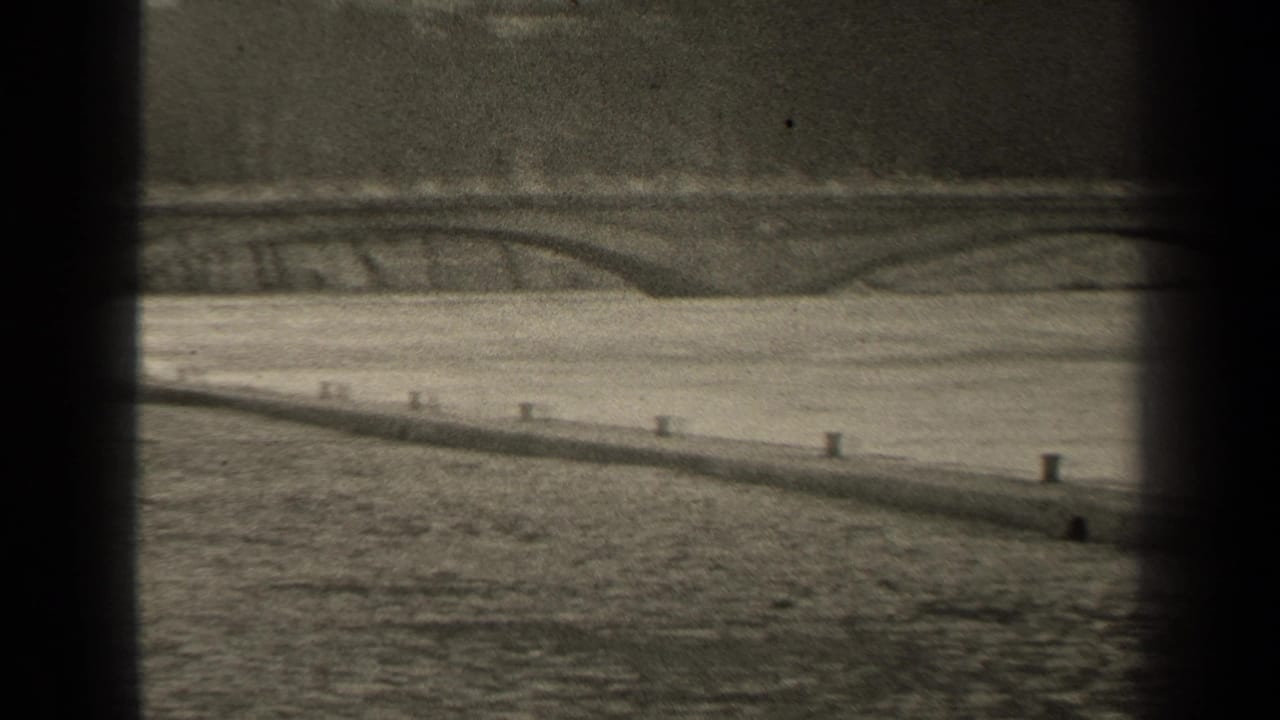 Paris riverside view with an arched bridge, masonry embankment, calm water, and dark 8mm frame borders.