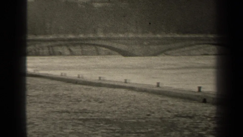 Paris riverside view with an arched bridge, masonry embankment, calm water, and dark 8mm frame borders.