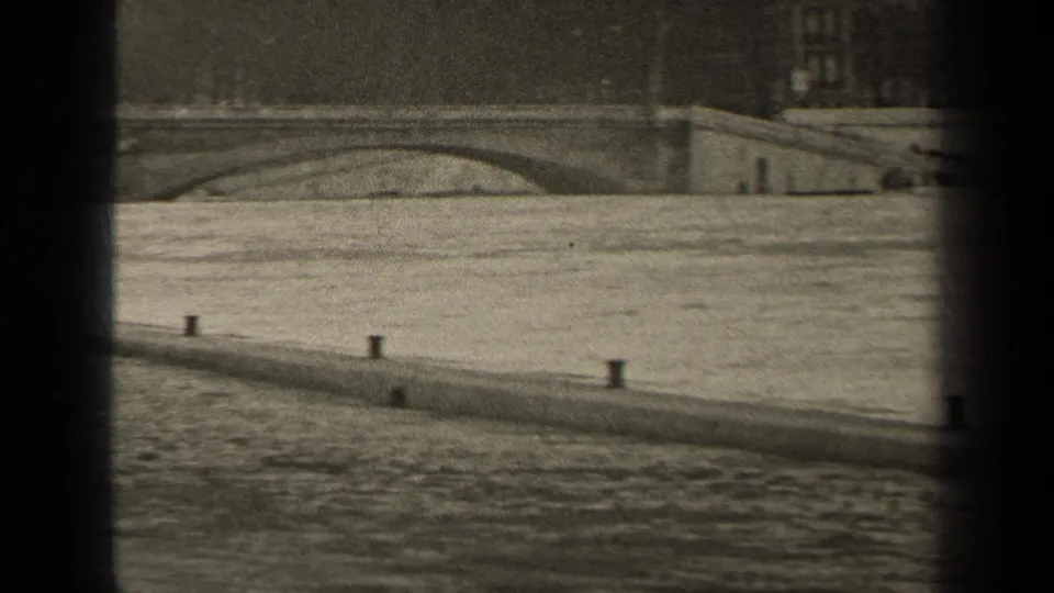 1947 Paris frame with river in the foreground, bollards on the embankment, and part of an arched bridge beyond.