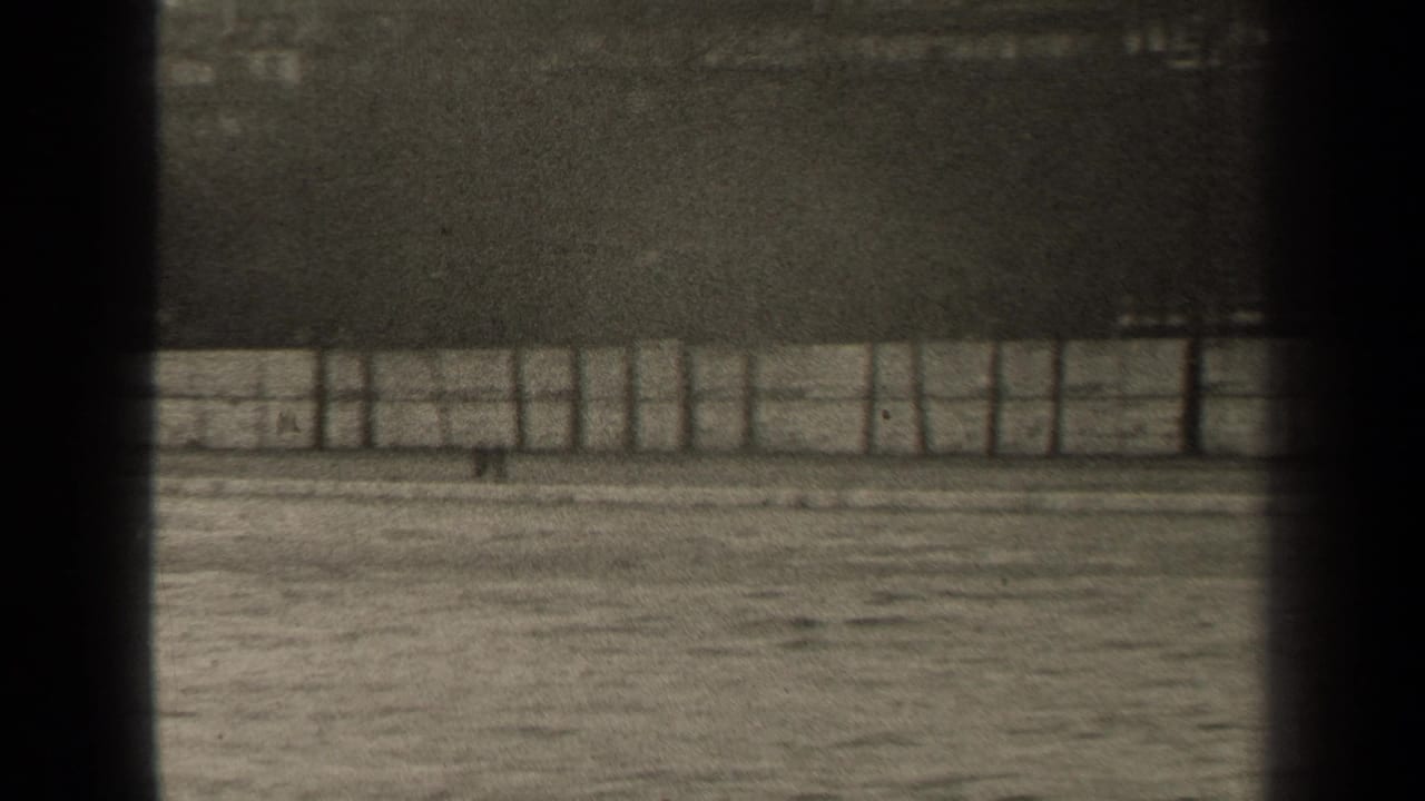 Riverside fence and water with a dark vertical band near the center.