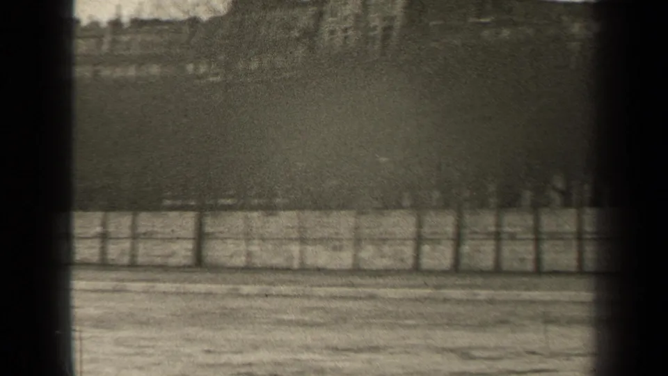 1947 Paris 8mm still with water in the foreground, riverside railing, bare trees, distant buildings, and heavy dark edge framing.