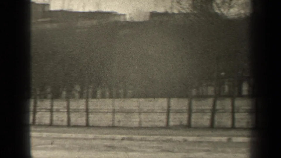 1947 Paris riverside frame showing water, fence, bare trees, distant buildings, and a small indistinct person near the railing.
