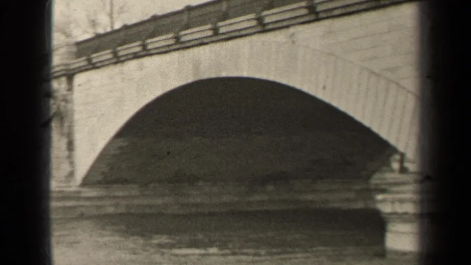 1947 Paris 8mm frame centered on a large stone bridge arch over moving river water, with railings along the top.