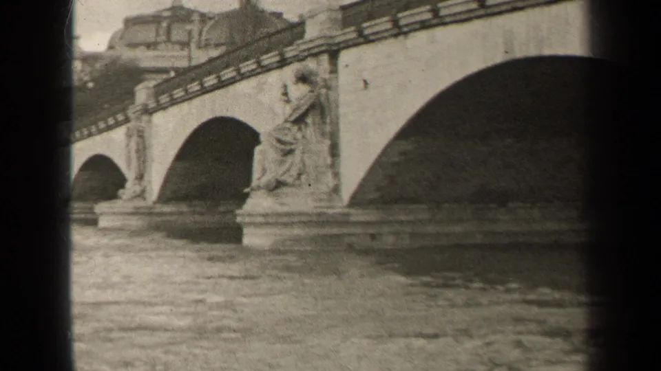 1947 Paris 8mm frame showing a seated bridge statue between arched spans, with river water in the foreground.