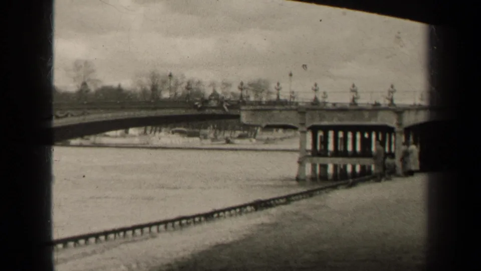 1947 Paris riverfront view showing the bridge, foreground embankment railing, and small people near the bridge support.