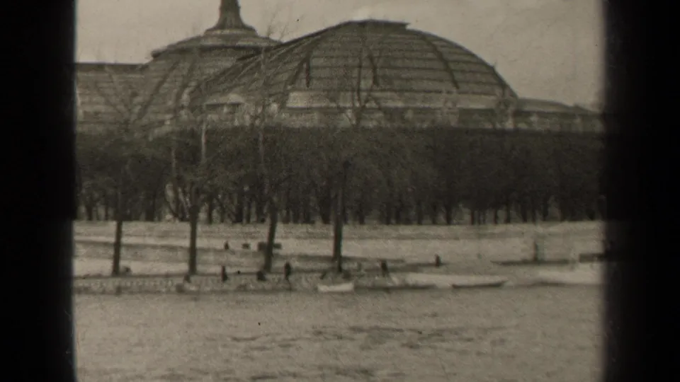 1947 Paris frame with a domed riverside building behind leafless trees, small pedestrians, and water in the foreground.