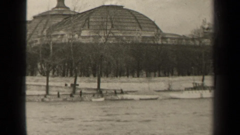 1947 Paris riverside view with small boats moored below bare trees and a large domed building beyond the bank.