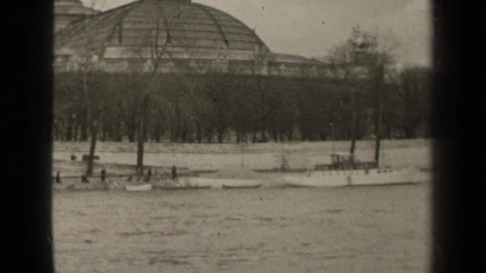 1947 Paris view across the river toward a domed building, leafless trees, and small boats tied along the bank.