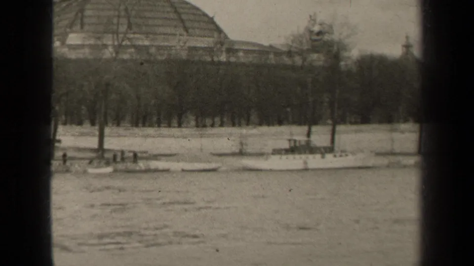 1947 Paris riverside frame showing moored boats, bare trees, and the edge of a large domed building in soft 8mm focus.