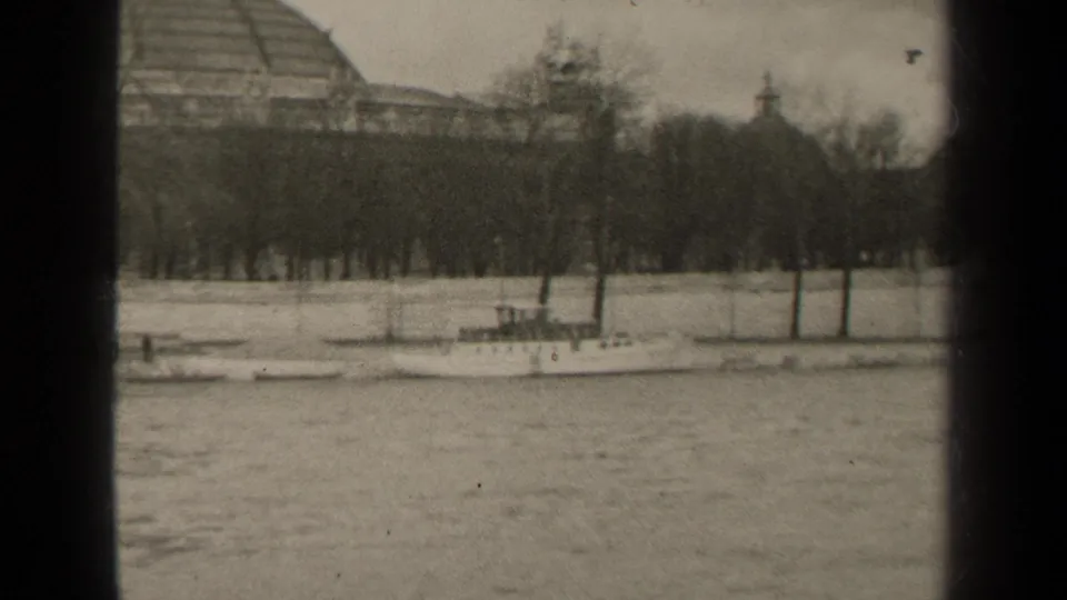 1947 Paris riverbank scene with boats at the shore, leafless trees, and the domed building partly obscured by framing.
