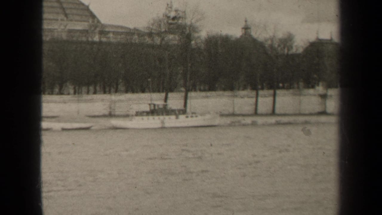 1947 Paris river view with a small boat, bare trees, stone embankment, and soft historic building silhouettes in the background.