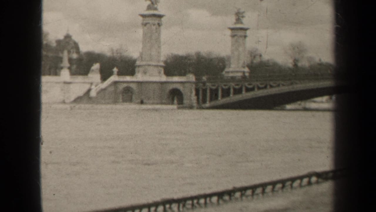 Wide black-and-white view of a stone bridge and river under a cloudy sky.