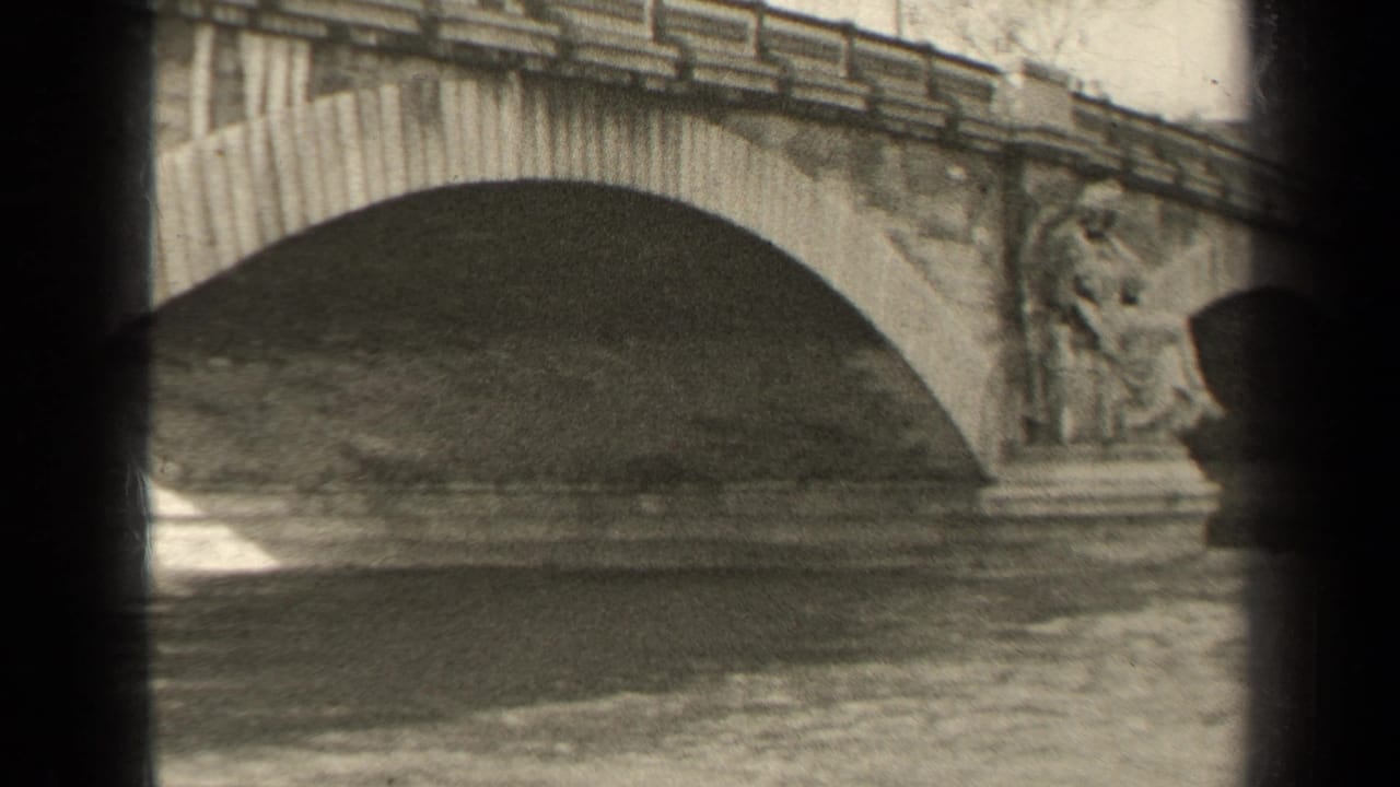 Arched stone bridge over rippled water, seen through dark film-frame borders.