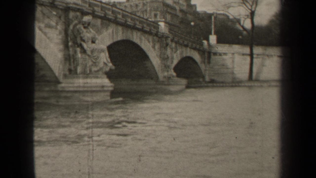 1947 Paris view of a historic stone bridge over the river, with sculptural details, embankment walls, bare trees, and soft 8mm framing.
