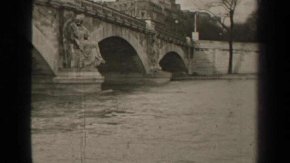 1947 Paris view of a historic stone bridge over the river, with sculptural details, embankment walls, bare trees, and soft 8mm framing.