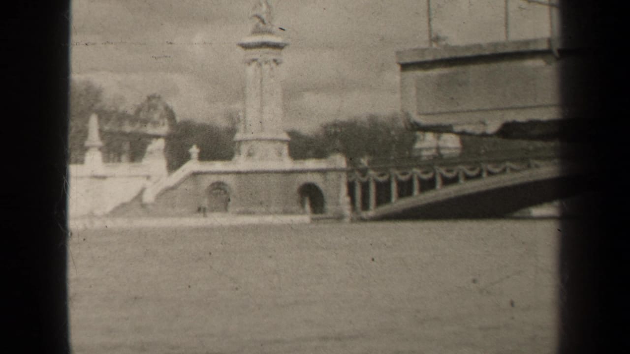 Bridge approach and monument seen across a river with dark film borders.