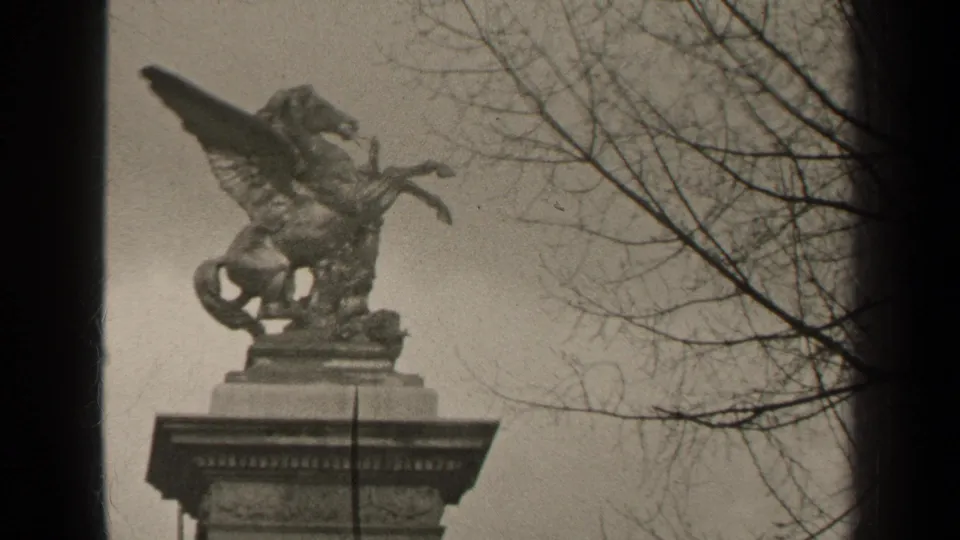 1947 Paris home-movie frame with a weathered Pegasus-like monument seen against an overcast sky and bare branches.