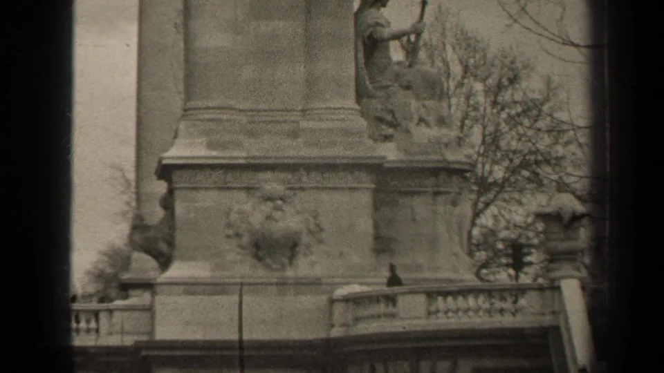 1947 Paris frame of a monument pedestal with a seated sculptural figure, decorative railing, and bare trees in the background.