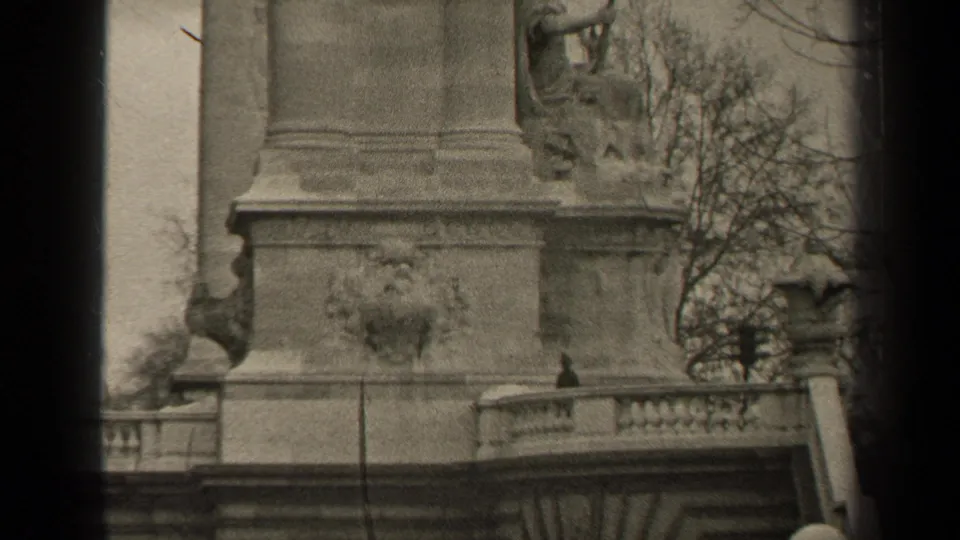 Black-and-white 1947 Paris 8mm view of the monument base, decorative reliefs, balustrade, and winterlike tree branches.