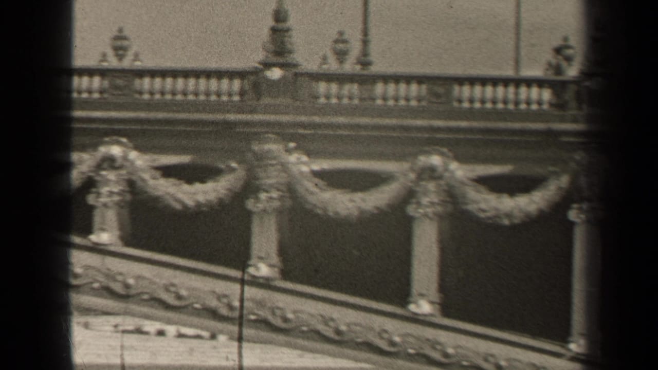 1947 Paris home-movie frame showing decorative stonework, balustrades, and garland-like ornament viewed through dark vertical foreground bars.